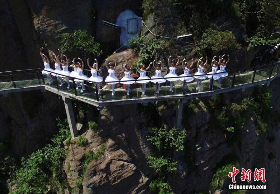 Dancers perform ballet on cliff, glass walkway