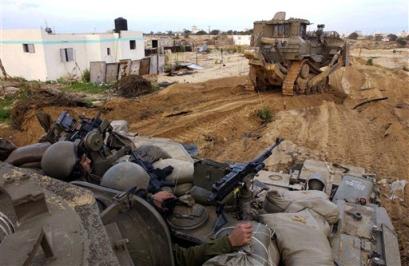 An Israeli army armored bulldozer clears a path for an armored personnel carrier during an operation against Palestinian militants Sunday Jan. 16, 2005 in the Zeitoun neighborhood near Gaza City in the Gaza Strip. The Israeli military received a green light on Sunday for a tough crackdown on Palestinian militants, as the government dismissed a call by the PLO leadership for a halt to attacks on Israelis. [AP]