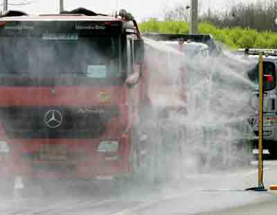 South Korean trucks returning from the inter-Korean industrial complex in North Korea's Kaesong after unloading construction materials pass through an anti-epidemic spray at Dorasan immigration office, near a demilitarised zone in Paju, about 55 km (34 miles) north of Seoul, April 22, 2005. South Korean officials travelled to the North Korean city of Kaesong on Friday for talks on helping the country combat a bird flu outbreak, Unification Ministry officials said. [Reuters]