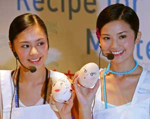 Hong Kong pop music group "Twins", Gillian Chung (L) and Charlene Choi, pose with eggs painted with cosmetics in Hong Kong May 31, 2005. Twins are promoting cosmetic products in the territory.