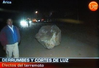 A resident in the northern Chilean port city of Arica appears next to a rock that fell from a hill in the city during strong earthquake that caused at least one dead and widespread damage in several Andean villages in Arica, Chile, Monday, June 13, 2005. 