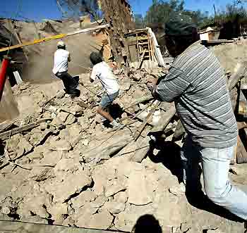 A group of men work in a street in Huara town, some 96 km (59 miles) off Iquique, about 1,845km (1,146 miles) north of Santiago, Chile, June 14, 2005. Boulders littered city streets and highways in northern Chile on Tuesday after a 7.9-magnitude quake caused landslides and wrecked homes, killing at least 11 and injuring 200. [Reuters]