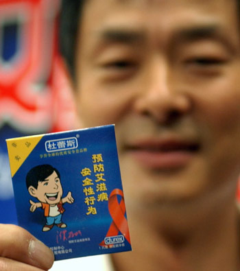 Chinese actor Pu Cunxin displays a condom with his cartoon photo on it to promote safe sex at a ceremony marking the World Populatio Day July 11, 2005. This year's World Population Day, which falls Monday, highlights the fight to empower women in the hope of better tackling the spread of HIV/AIDS. There are 840,000 people in China who are HIV positive, and 80,000 have developed AIDS. The United Nations warns that 10 million people could be infected in the country by 2010 if preventative measures are not taken. [newsphoto]