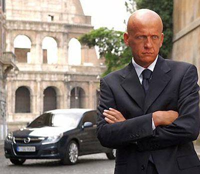 Italian referee Pierluigi Collina poses in front of Opel cars in a promotional photograph released by the auto maker August 29, 2005. The sudden resignation of referee Pierluigi Collina has left many Italians debating whether soccer's best-known match official was forced to quit. The five-times world referee of the year resigned from the Italian Association of Referees (AIA) on Monday after refusing to renounce an 800,000-euros per year sponsorship deal with German car manufacturer Opel. Picture released August 29, 2005. [Reuters]