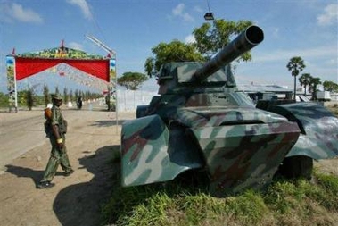 A Tamil rebel of the Liberation Tigers of Tamil Eelam walks past a abandoned, repainted battle tank at the rebel controlled town of Elephant Pass, about 270 kilometers (169 miles) north of Colombo, Sri Lanka, Sunday, Nov. 27, 2005. 